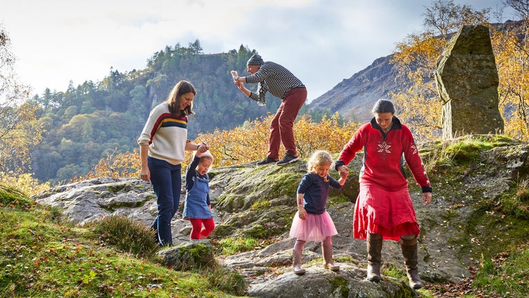 A family explores around the Bowderstone on a sunny Autumn day